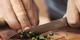 man die bieslook snijdt op een snijplank

