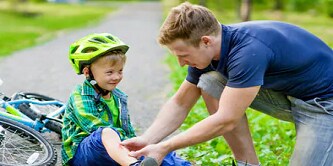 man helpt een kind nadat dit met de fiets is gevallen 
