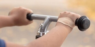 Hand op stuur van fiets met Nexcare™ DUO-pleister
